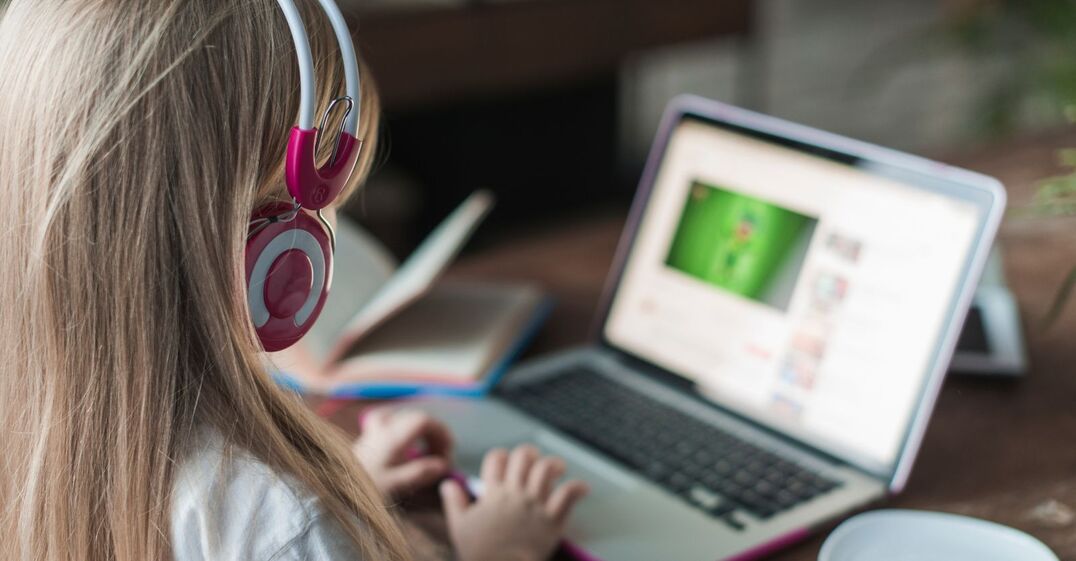Blond girl wearing headphones looking at laptop